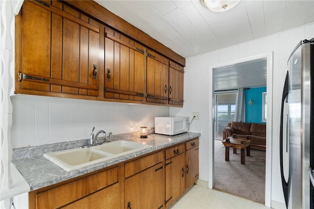 kitchen with light carpet, stainless steel refrigerator, and sink