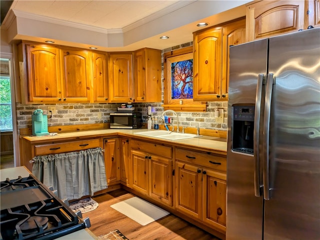 kitchen featuring backsplash, stainless steel appliances, ornamental molding, sink, and light wood-type flooring