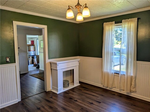 spare room with a wealth of natural light, dark wood-type flooring, a chandelier, and crown molding