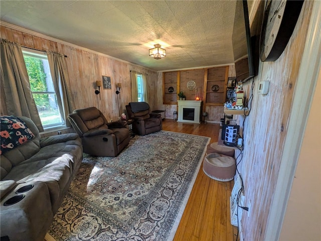 living room with ornamental molding, wood walls, and hardwood / wood-style flooring