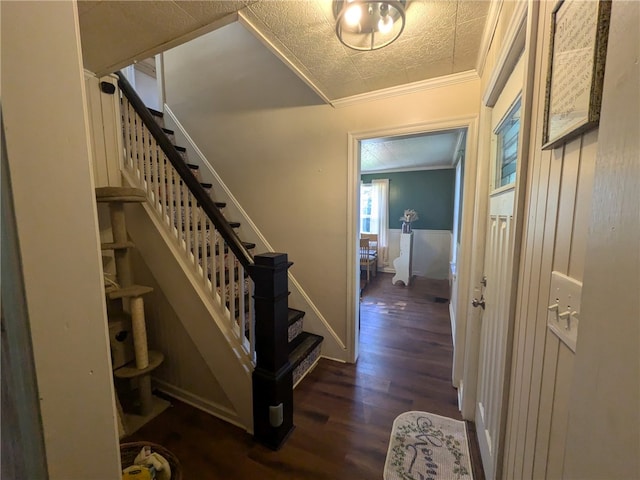 stairway with ornamental molding, a textured ceiling, and hardwood / wood-style floors