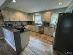 kitchen featuring light hardwood / wood-style flooring, kitchen peninsula, stainless steel appliances, and backsplash