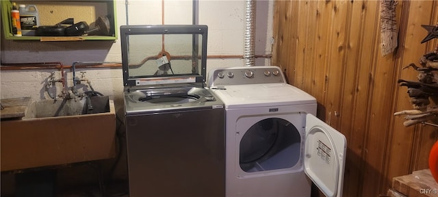 washroom with washer and clothes dryer and wood walls