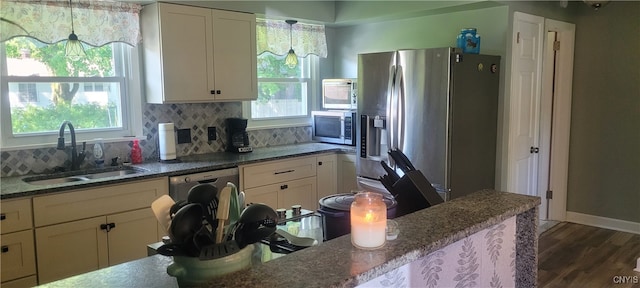 kitchen featuring hanging light fixtures, stainless steel appliances, sink, tasteful backsplash, and dark hardwood / wood-style flooring