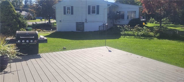 wooden deck featuring a yard and a grill