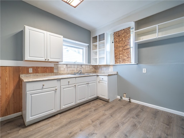 kitchen with light hardwood / wood-style flooring, backsplash, sink, and white cabinets