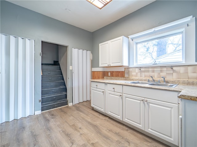 kitchen featuring white cabinetry, light hardwood / wood-style flooring, and sink