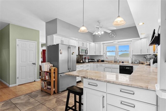 kitchen featuring kitchen peninsula, hanging light fixtures, white cabinetry, light hardwood / wood-style flooring, and stainless steel appliances