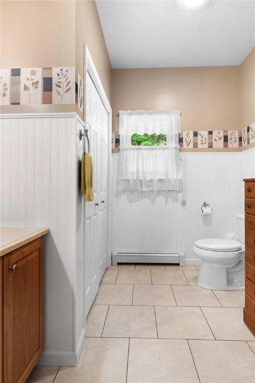 bathroom with toilet, vanity, tile patterned floors, and a baseboard radiator