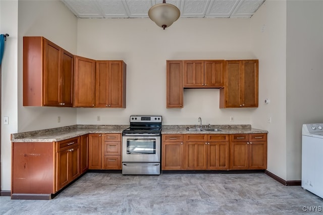 kitchen with light stone countertops, stainless steel electric range, washer / dryer, sink, and a towering ceiling