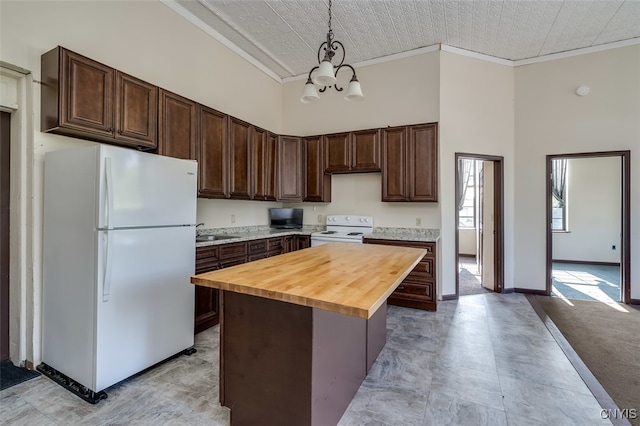 kitchen featuring white appliances, a chandelier, dark brown cabinets, pendant lighting, and a kitchen island