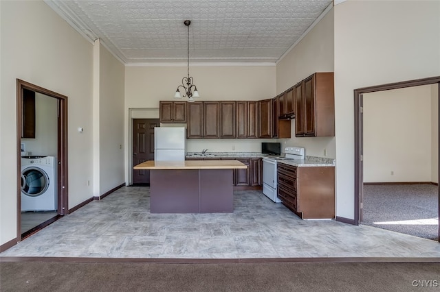 kitchen with washer / dryer, white appliances, a kitchen island, and light carpet