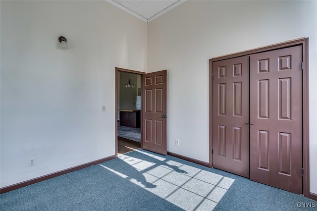 unfurnished bedroom featuring dark carpet, a closet, and crown molding