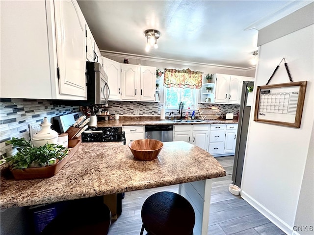 kitchen featuring ornamental molding, stainless steel appliances, sink, a breakfast bar, and white cabinets