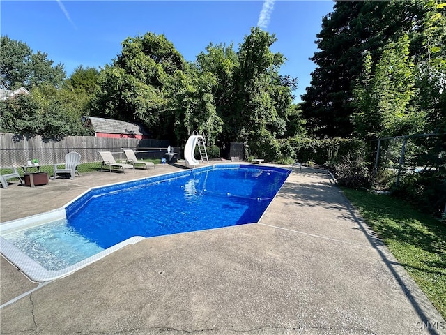 view of swimming pool with a water slide and a patio