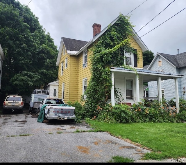 view of side of home featuring a yard and covered porch