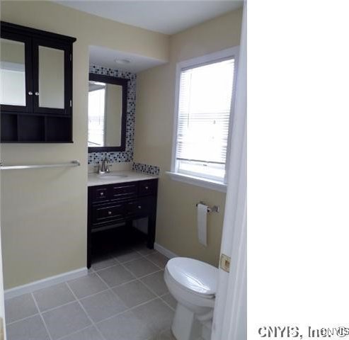 bathroom with tile patterned flooring, vanity, toilet, and tasteful backsplash