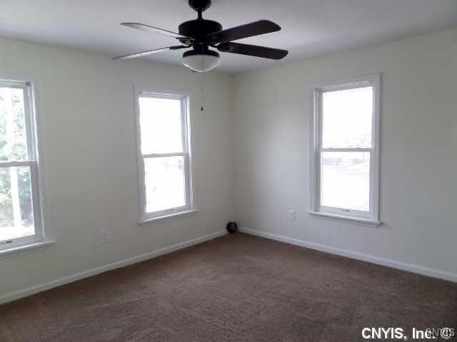 unfurnished room with dark carpet and ceiling fan