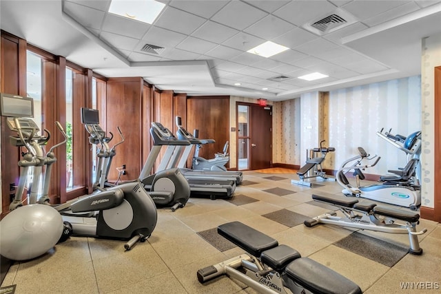 gym featuring a paneled ceiling and a raised ceiling