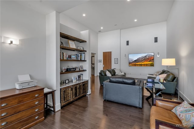 living room featuring dark hardwood / wood-style flooring and a towering ceiling