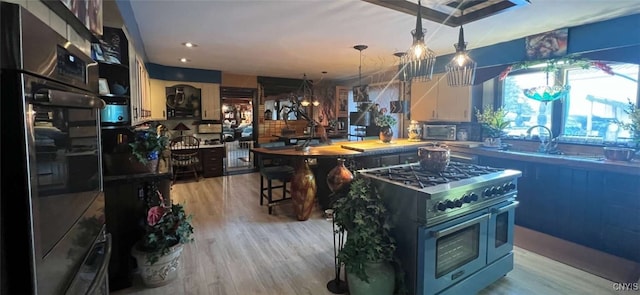 kitchen with a center island, stainless steel appliances, white cabinetry, and light hardwood / wood-style flooring