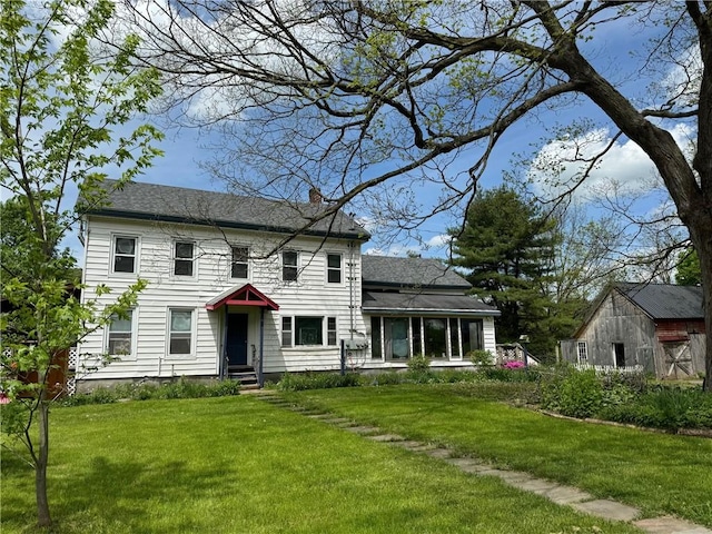 colonial inspired home featuring a front lawn and a chimney