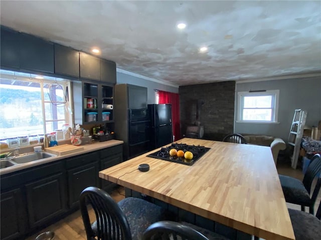 kitchen with a breakfast bar area, wood finished floors, a sink, black appliances, and ornamental molding