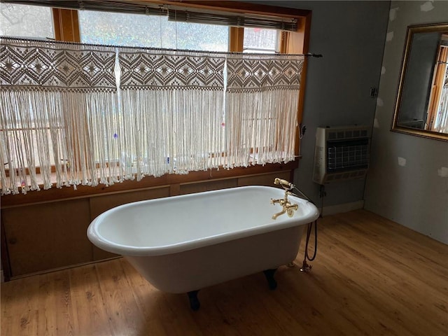 bathroom featuring heating unit, a freestanding tub, and wood finished floors