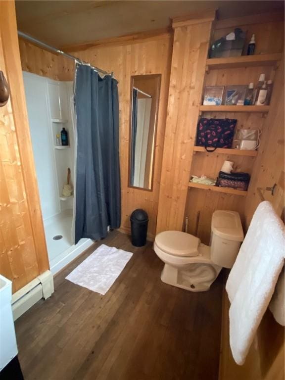 bathroom with a shower stall, wood walls, wood finished floors, a baseboard heating unit, and toilet