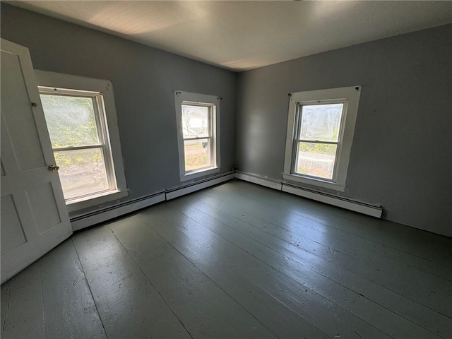 unfurnished room featuring wood-type flooring, baseboard heating, and a wealth of natural light