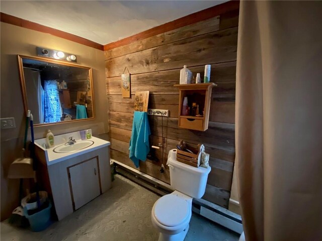 bathroom featuring wooden walls, vanity, a baseboard heating unit, and toilet