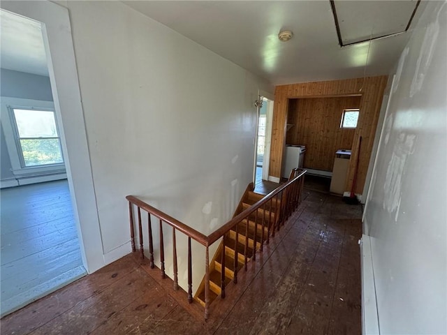 hallway featuring attic access, wood walls, hardwood / wood-style flooring, a baseboard heating unit, and an upstairs landing