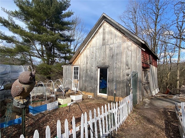 view of outbuilding with fence, a garden, and an outbuilding