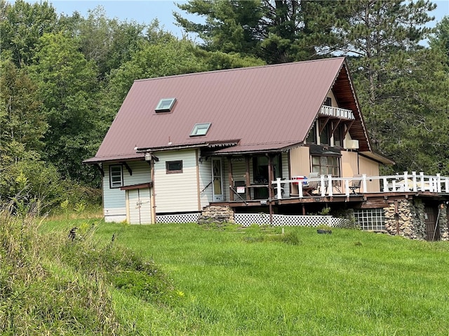 back of property featuring a wooden deck and a lawn