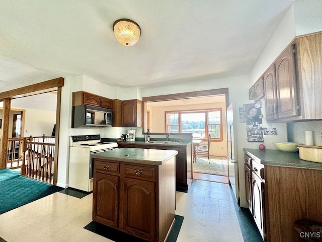 kitchen featuring white range with electric stovetop, sink, and kitchen peninsula