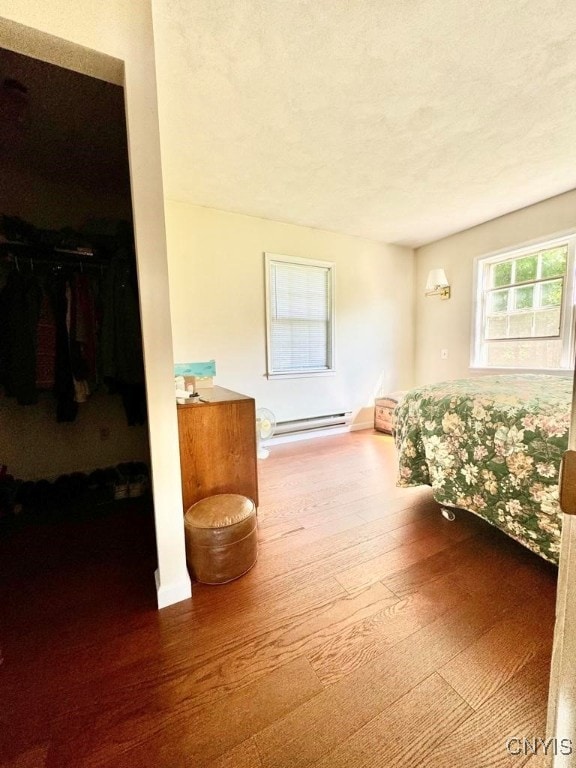 interior space featuring a baseboard heating unit, hardwood / wood-style flooring, and a textured ceiling