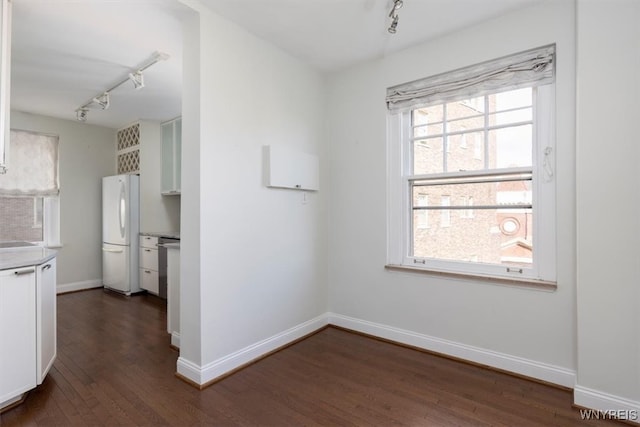 kitchen with white fridge, white cabinetry, track lighting, and dark hardwood / wood-style flooring