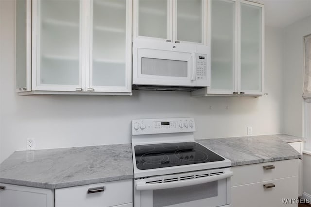 kitchen featuring white appliances, light stone counters, and white cabinetry