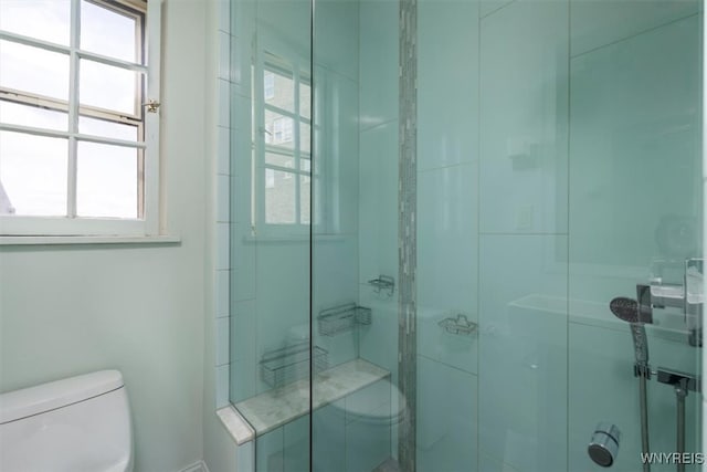 bathroom featuring a shower with door and toilet