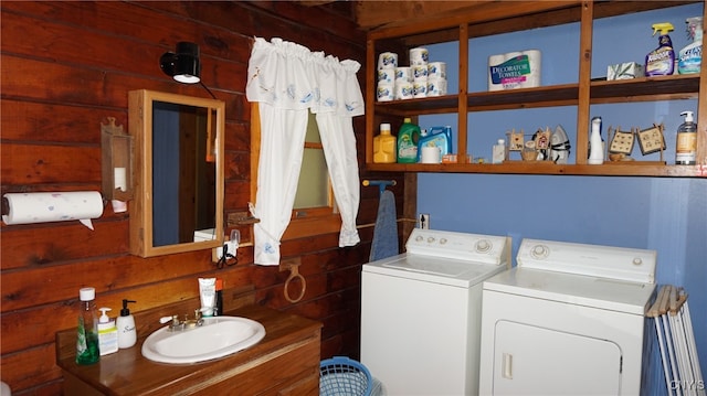 laundry area featuring independent washer and dryer, sink, and wooden walls