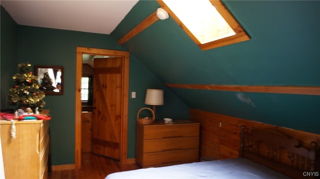 bedroom featuring hardwood / wood-style floors and lofted ceiling with skylight