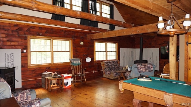 playroom featuring beamed ceiling, a wood stove, billiards, hardwood / wood-style flooring, and a high ceiling