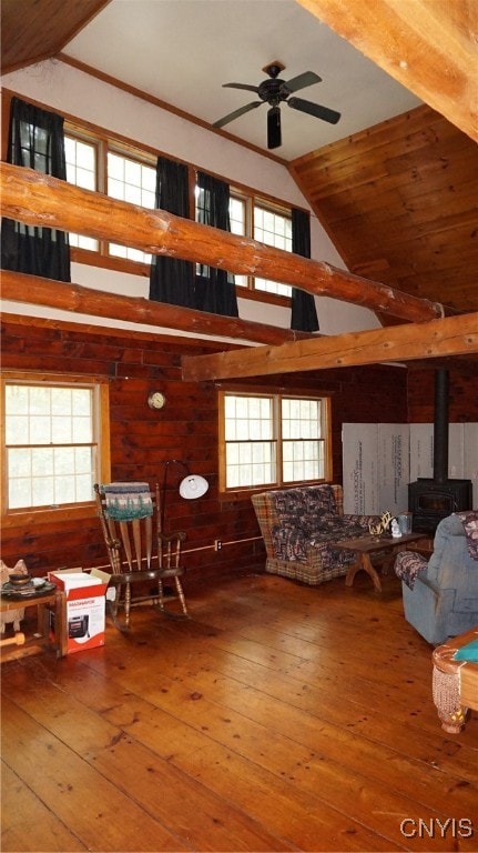 misc room featuring vaulted ceiling, a wood stove, hardwood / wood-style floors, ceiling fan, and wooden walls