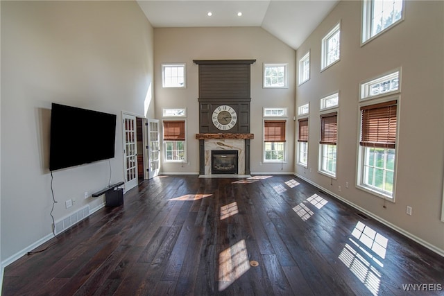 unfurnished living room with a high ceiling, a high end fireplace, and dark hardwood / wood-style floors