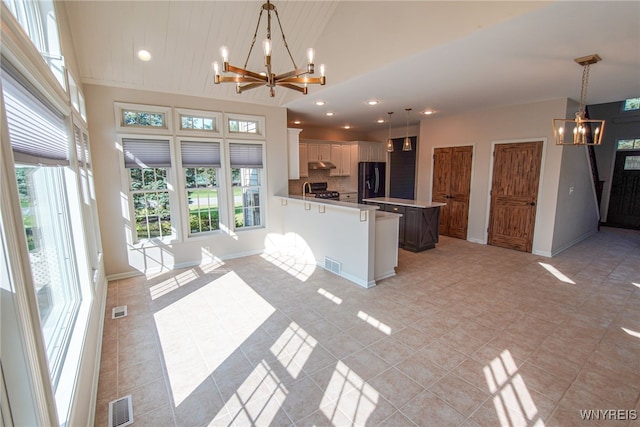 kitchen featuring decorative light fixtures, a notable chandelier, light tile patterned floors, white cabinetry, and black refrigerator