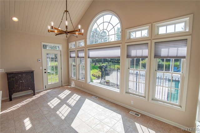 unfurnished sunroom with vaulted ceiling, a notable chandelier, and a healthy amount of sunlight