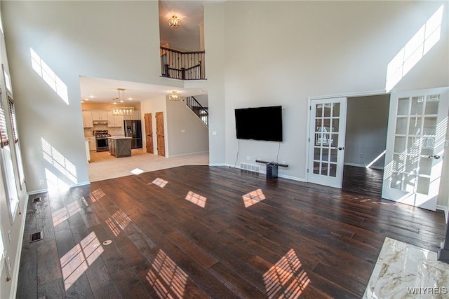 unfurnished living room with a high ceiling, a notable chandelier, and hardwood / wood-style flooring