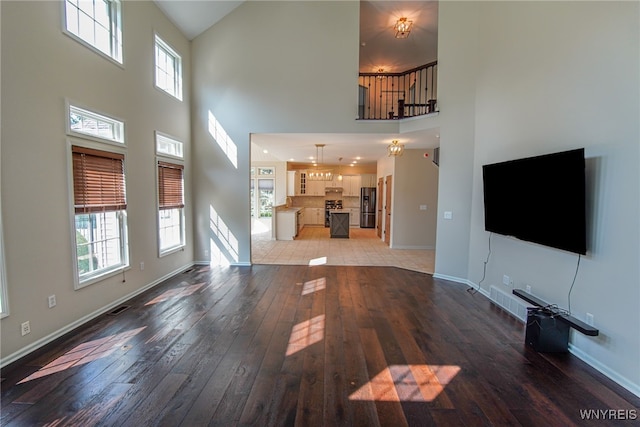 unfurnished living room featuring light hardwood / wood-style flooring and a towering ceiling