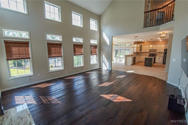 unfurnished living room featuring light wood-type flooring and a high ceiling