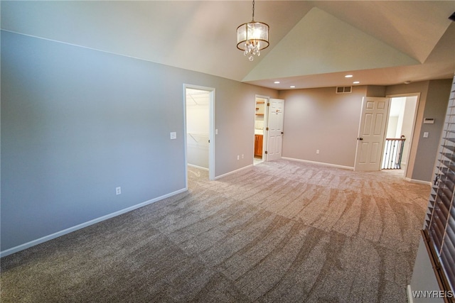 carpeted empty room featuring lofted ceiling and a notable chandelier